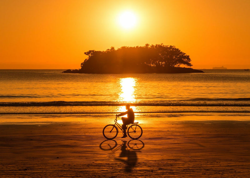 person-riding-their-bike-at-sunset-along-the-beach